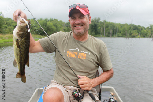 An angler with a largemouth bass caught while fishing from a small boat 