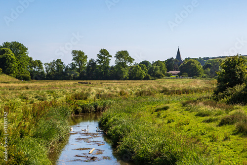 A view of Alfriston Church in the South Downs, with swans swimming on the Cuckmere river in the foreground photo