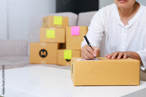 Entrepreneurs are packing boxes at home, Small business selling ideas for sme, Pack products to send to customers, woman writing something on paper, home delivery concept.