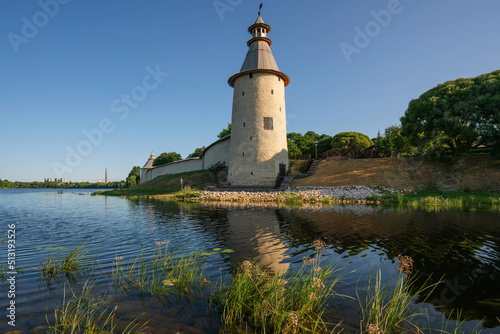 View of the wall of the Pskov Kremlin and High (Vysokaya) tower on the bank of the Pskova River on a sunny summer day, Pskov, Russia