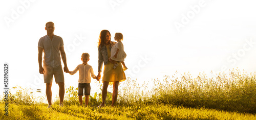 Happy loving family walking outdoor in the light of sunset. Father, mother, son and daughter.