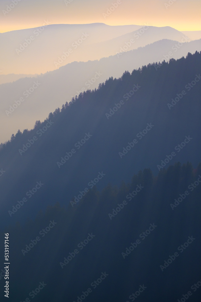 Graphic Layers of mountains shrouded in haze with rays of sun shining through the treetops Graphic Layers of mountains shrouded in haze with rays of sun shining through the treetops