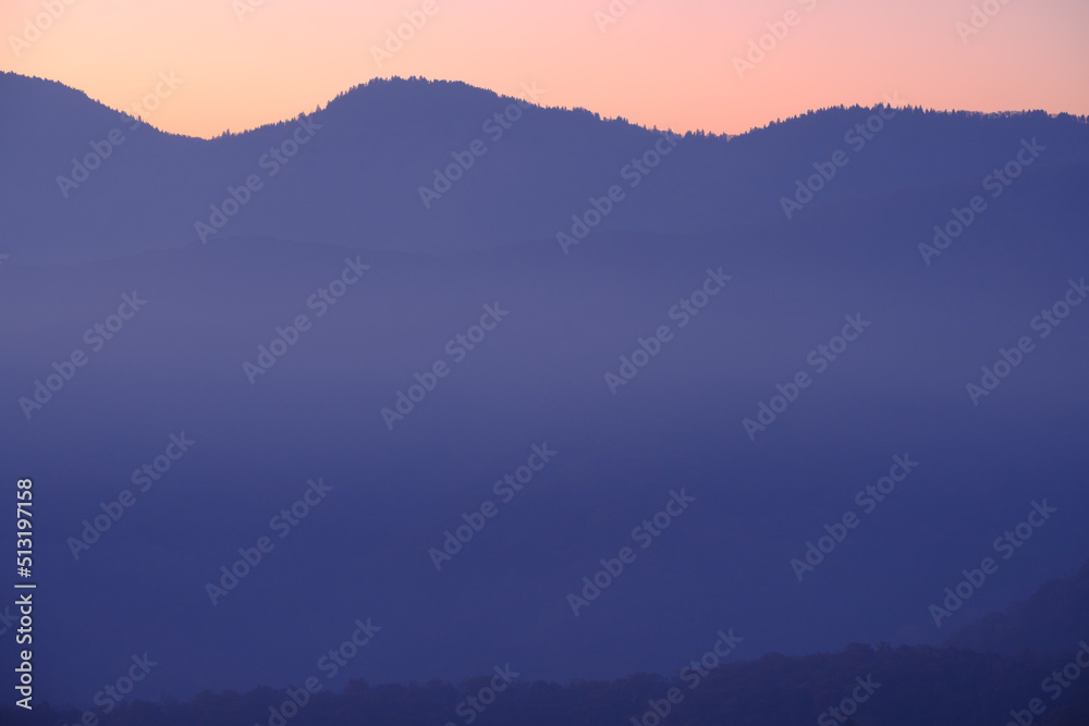Fototapeta premium subtle purple and orange sunrise hues in a simple mountain landscape