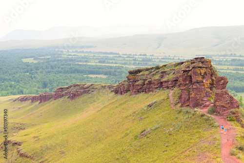 Tourists walking to trail on First Sunduk of the mountain range Sunduki. Located in the valley of the Bely Iyus River. Summer landscape of the Sunduki mountain range in Khakassia, Russia. photo