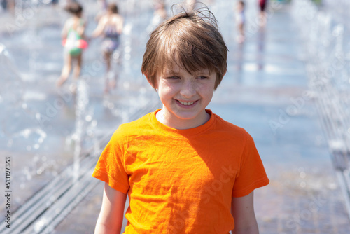 portrait of a happy boy in a orange t-shirt stands in a dry fountain