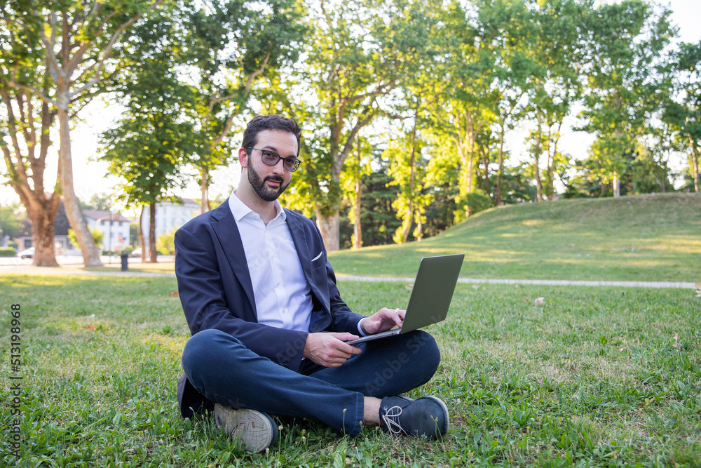 Young entrepreneur in the park answers an email while sitting on the grass. Work anywhere Young entrepreneur in the park answers an email while sitting on the grass. Work anywhere