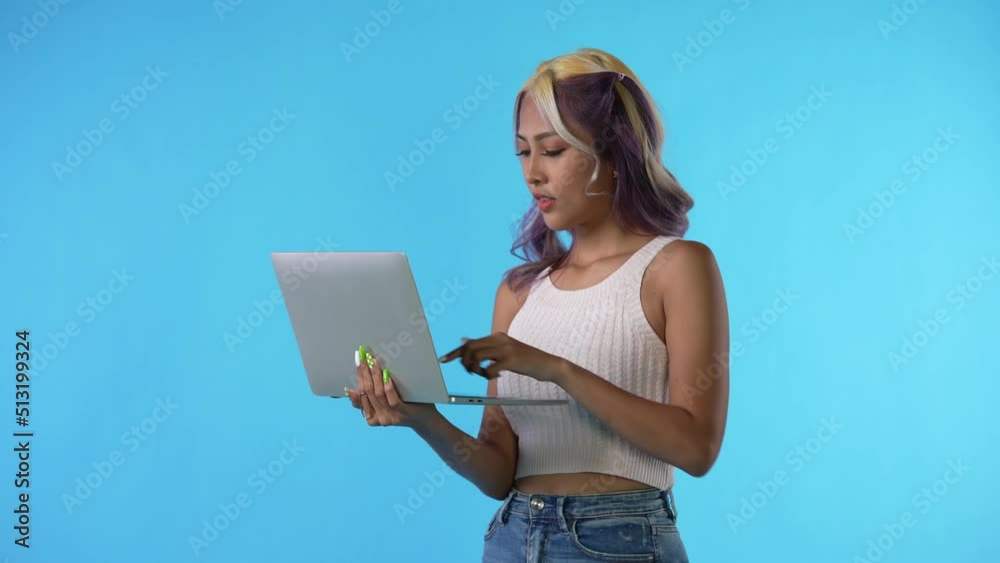 Young Asian woman using laptop isolated on blue background Young Asian woman using laptop isolated on blue background