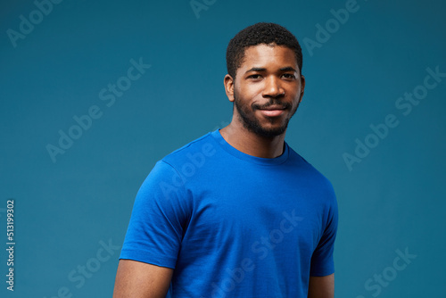 Portrait of smiling black man wearing blue shirt on vibrant blue background and looking at camera, copy space