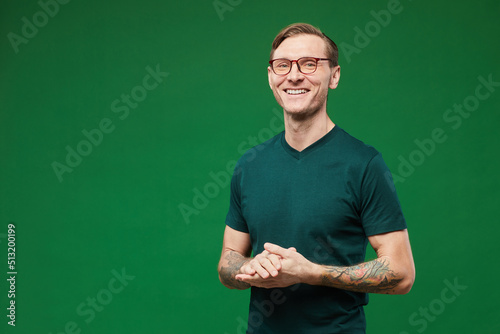 Photography Waist up portrait of tattooed man wearing green shirt and glasses against vibran
