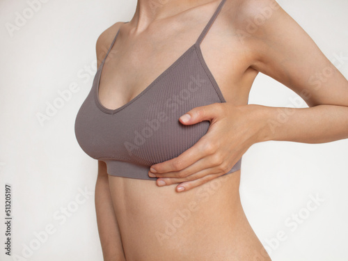 Closeup cropped portrait young woman with breast pain touching chest  
woman examining breast mastopathy or cancer 
plastic surgery White background Healthcare concept. women Health. White background photo