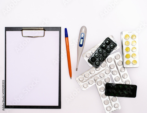 A universal tablet, a notebook for writing a prescription by a doctor, a medical thermometer and medicines on the table. copy space.