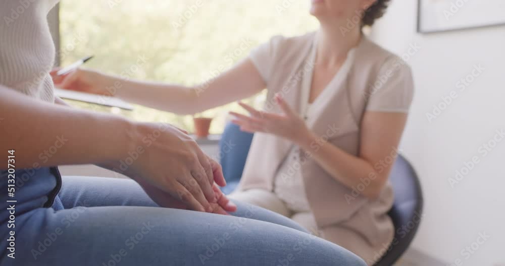 Closeup of unknown woman sitting with her physiotherapist in a clinic. Patient visiting therapist during consult and explaining her injury while suffering from knee pain. Seeking professional massage Closeup of unknown woman sitting with her physiotherapist in a clinic. Patient visiting therapist during consult and explaining her injury while suffering from knee pain. Seeking professional massage