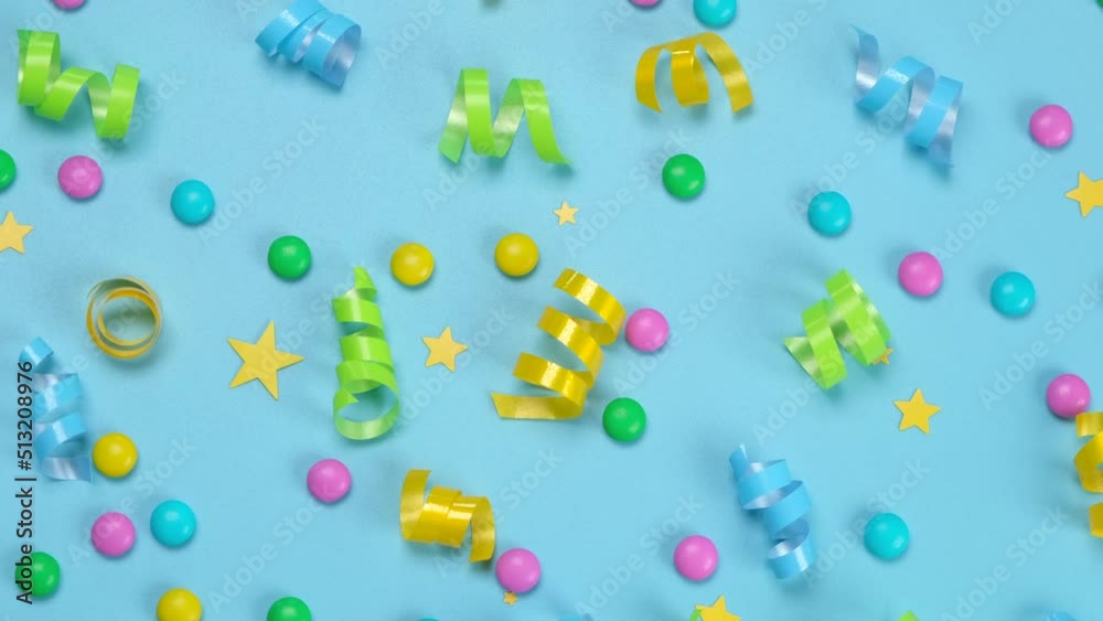 Rotating blue background with colorful candies and serpentine or ribbons on blue background, concept for birthday, anniversary, congratulations Rotating blue background with colorful candies and serpentine or ribbons on blue background, concept for birthday, anniversary, congratulations