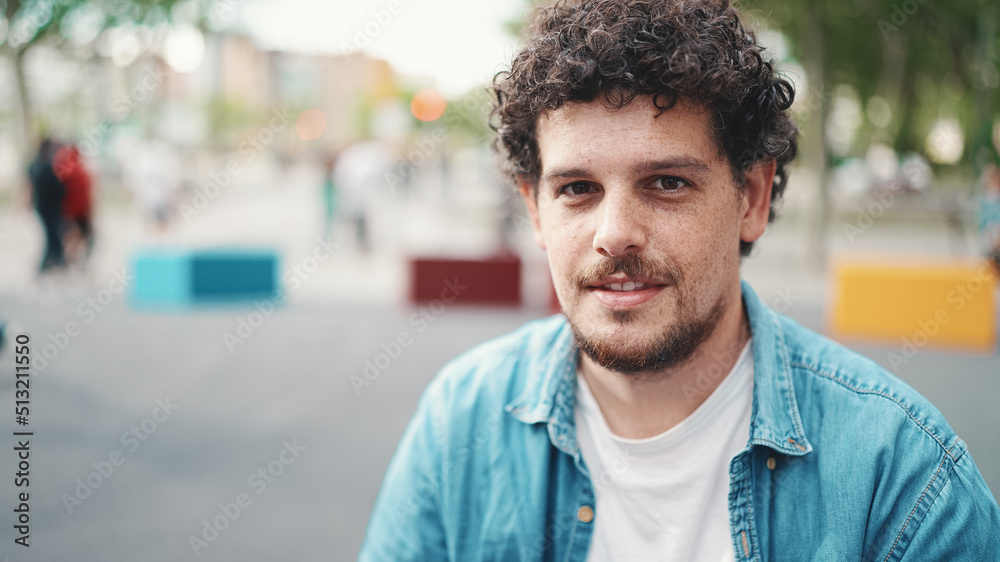 closeup portrait of young bearded man in denim shirt posing and smiling at camera on modern cityscape background. closeup portrait of young bearded man in denim shirt posing and smiling at camera on modern cityscape background.