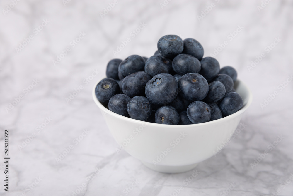 Blueberry. Ripe and fresh blueberries in a plate on a marble background. Vitamins. Healthy food. Juicy berry. Copy space. Place for text Blueberry. Ripe and fresh blueberries in a plate on a marble background. Vitamins. Healthy food. Juicy berry. Copy space. Place for text
