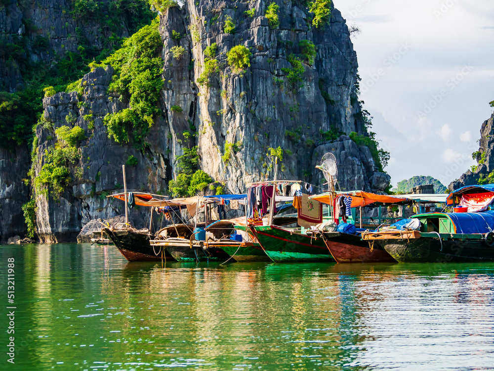 Obraz premium Multicolored fishing boats reflected in the emerald waters of Ha Long bay, Vietnam 