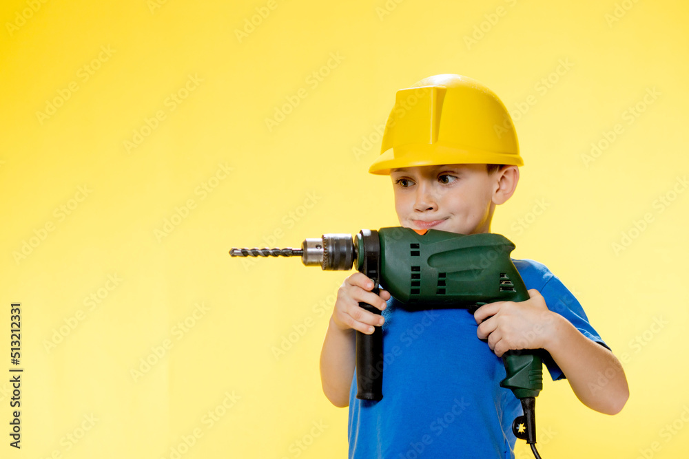 Smiling boy builder in a blue shirt holding a drill