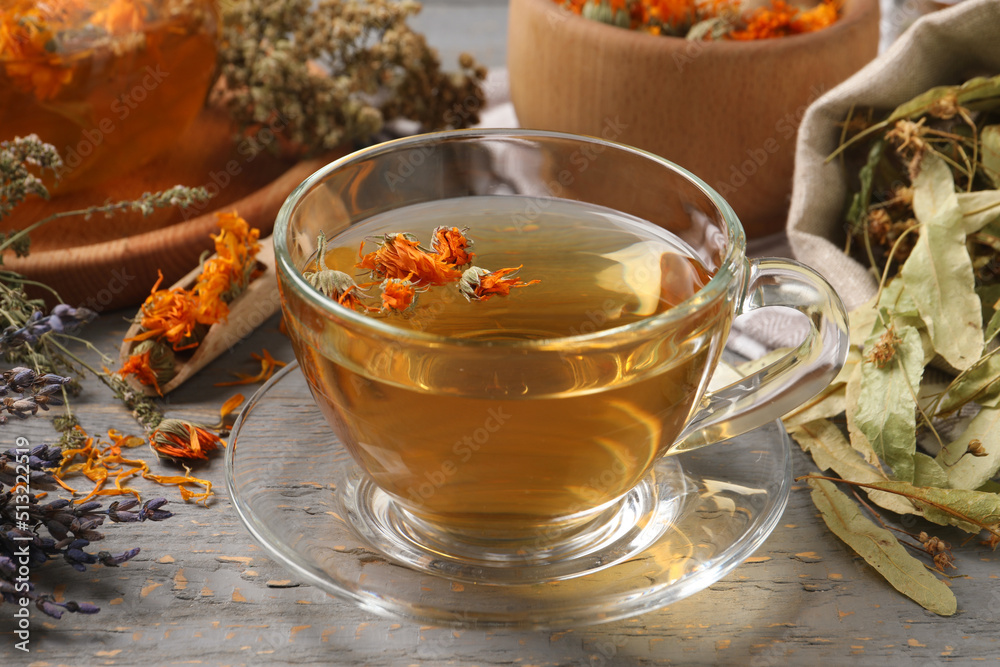 Freshly brewed tea and dried herbs on grey wooden table, closeup Freshly brewed tea and dried herbs on grey wooden table, closeup