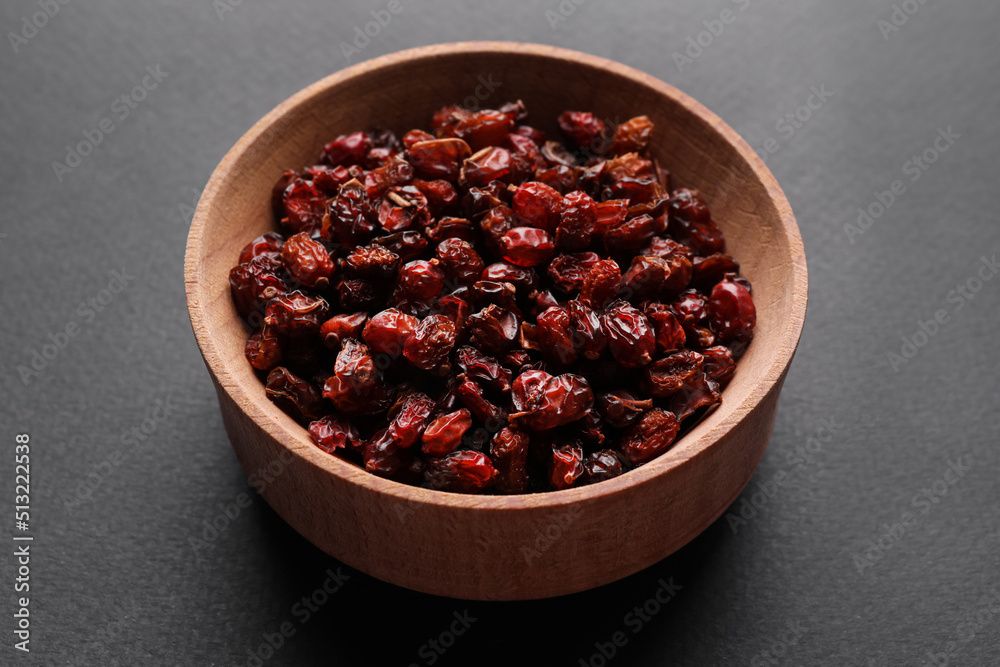 Dried barberries in wooden bowl on grey background