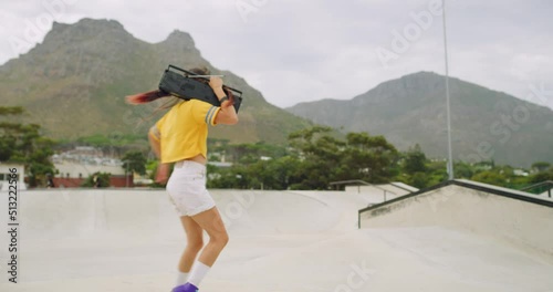 Carefree passionate skater spinning and listening to music on boombox while rollerskating in skate park and rink. One cool young fun woman enjoying free time and dancing while wearing rollerskates