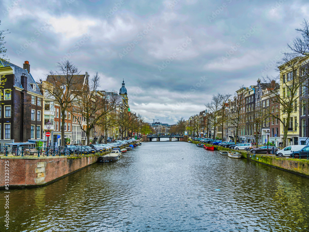 Fototapeta premium Dutch buildings and canal on a cloudy day in Amsterdam, Netherlands