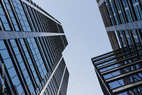 The view of the sky between strict skyscrapers. Modern office buildings in the financial district. Glass towers in downtown of the city. A cluster of tall buildings.