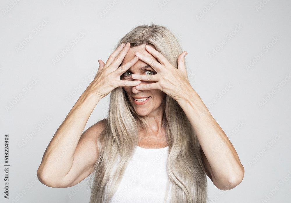 mature woman 60 years old with long hair closes her eyes with her palm on grey color background mature woman 60 years old with long hair closes her eyes with her palm on grey color background