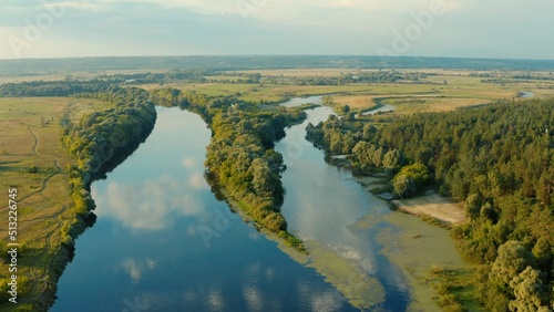 Aerial view above a beautiful landscape with a  river while sunset. Aerial view from drone flies over a beautiful summer landscape.