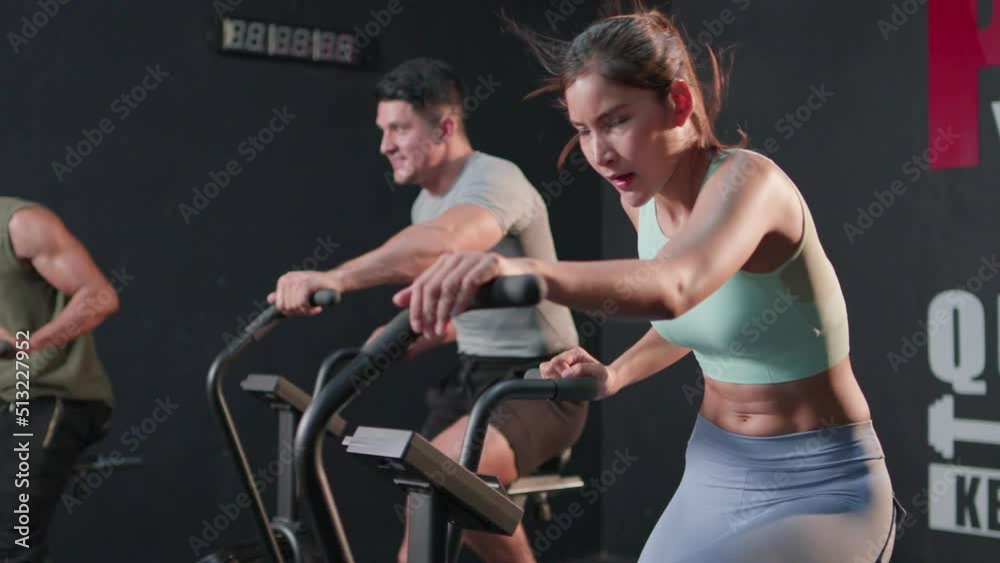 Group of people athlete workout on exercise with concentration in crossfit gym. diversity of man, woman during use equipment air bike spinning motion cardio training indoor. Healthy lifestyle concept.