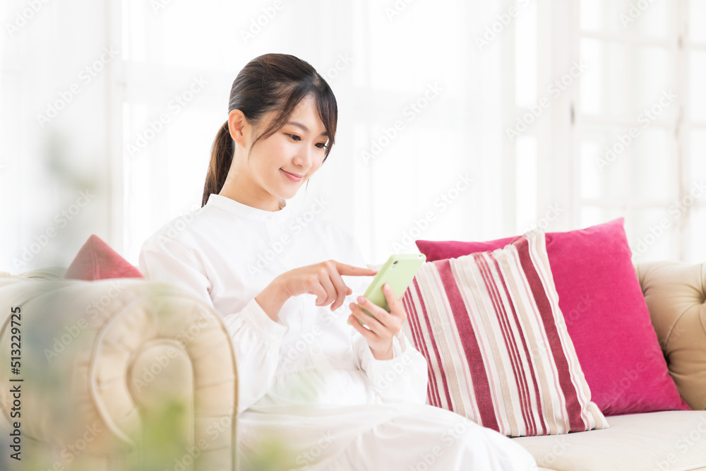 部屋でスマホを見る女性 部屋でスマホを見る女性