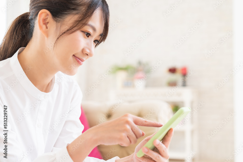 部屋でスマホを見る女性 部屋でスマホを見る女性