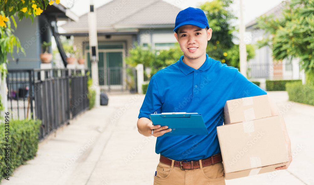 Asian young delivery man courier in uniform hold parcel post boxes service shipment and walking finding and looking for customer home location, Online shopping service concepts Asian young delivery man courier in uniform hold parcel post boxes service shipment and walking finding and looking for customer home location, Online shopping service concepts