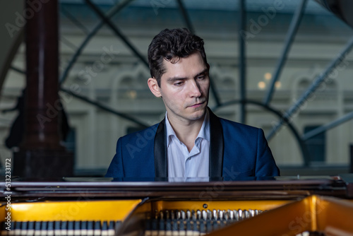 Pianist man plays grand piano in the classroom at evening