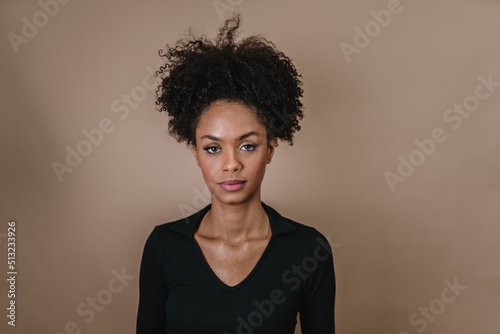 Closeup of a smiling young Latin afro woman. Joy, positive and love. Beautiful african-style hair. Pastel studio background. © Brastock Images
