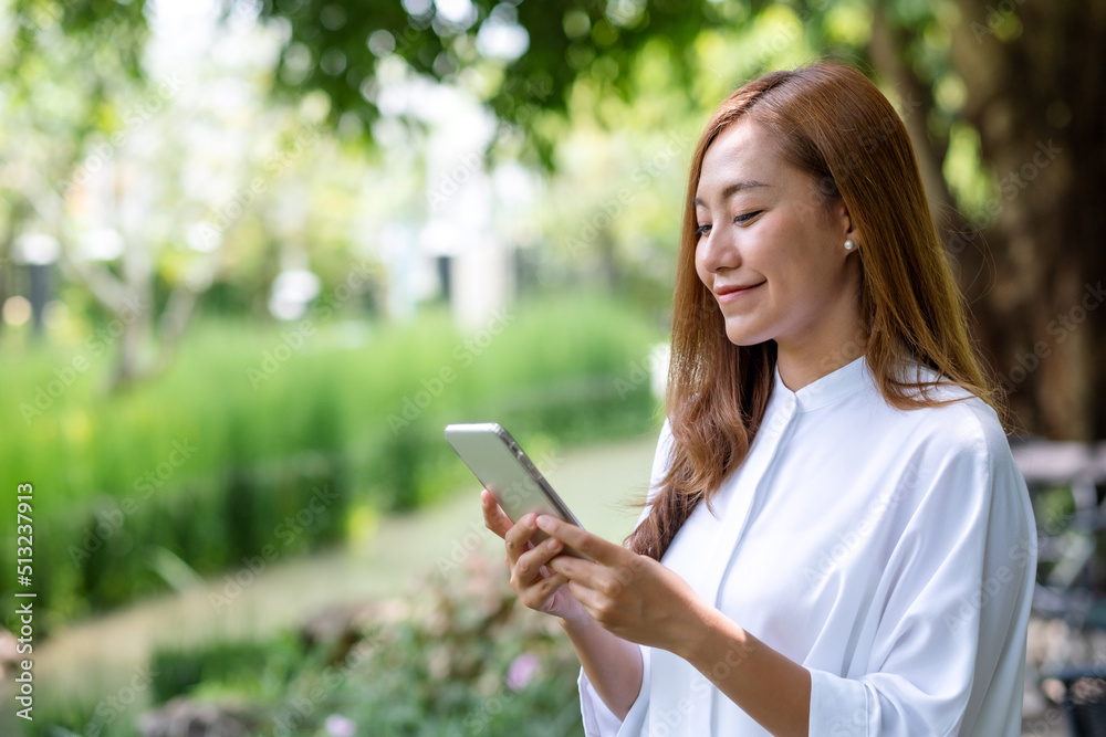 Portrait image of a beautiful young woman holding and using mobile phone in the outdoors Portrait image of a beautiful young woman holding and using mobile phone in the outdoors