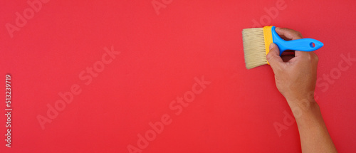 hand hold blue paint brush isolated on red background