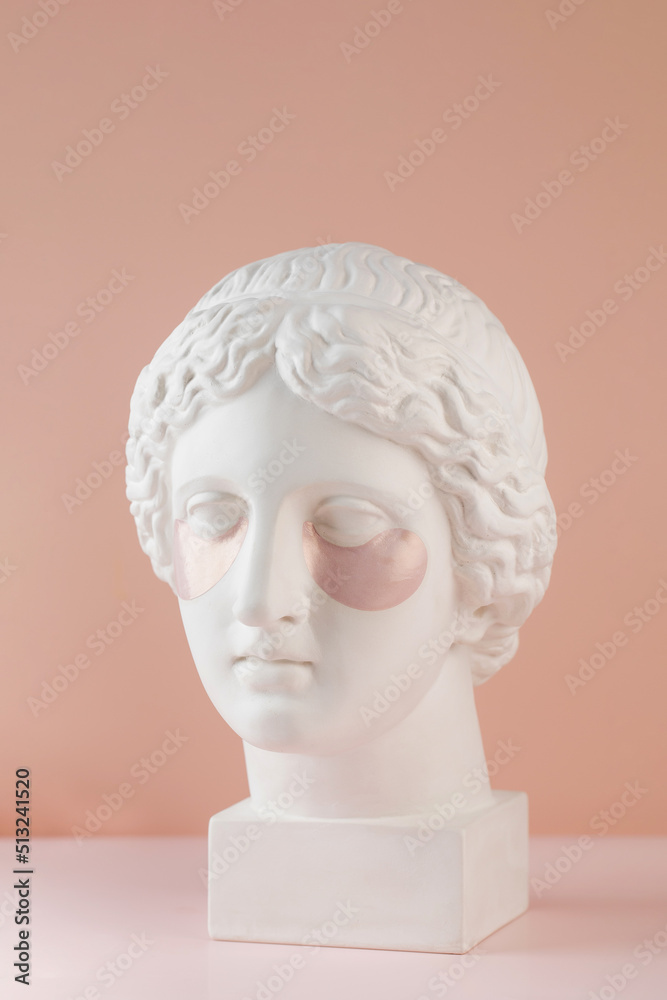 Hydrogel pink patches on the plaster head of Aphrodite on a pink background. Beauty concept. Hydrogel pink patches on the plaster head of Aphrodite on a pink background. Beauty concept.