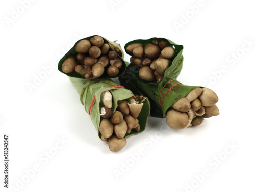 Ready-to-cook termite mushrooms wrapped in leaves isolated on white background. photo