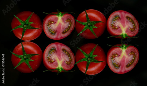 Two red whole and one half-cut tomatoes. isolated on black background. photo