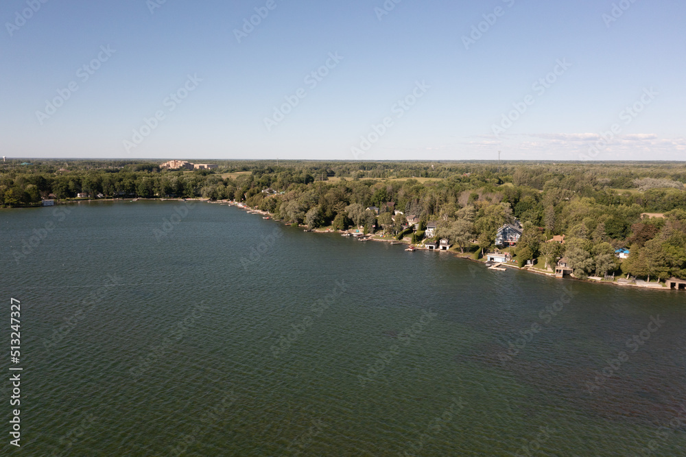 Orillia lake front green trees and lake blue skies drone shot 