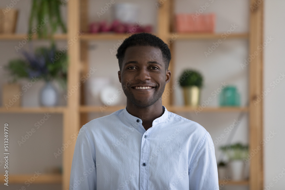 Obraz premium Head shot portrait successful young African businessman wear casual blue shirt smile looks at camera pose at workplace in cozy office. Professional occupation person, teacher profile picture concept