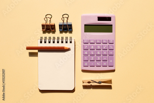 Notepad  colored pencil  calculator on beige background. top view  copy space