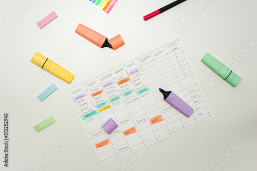 School schedule. A sheet with a handwritten school schedule lies on a white table strewn with colorful markers and stickers. School Time Management