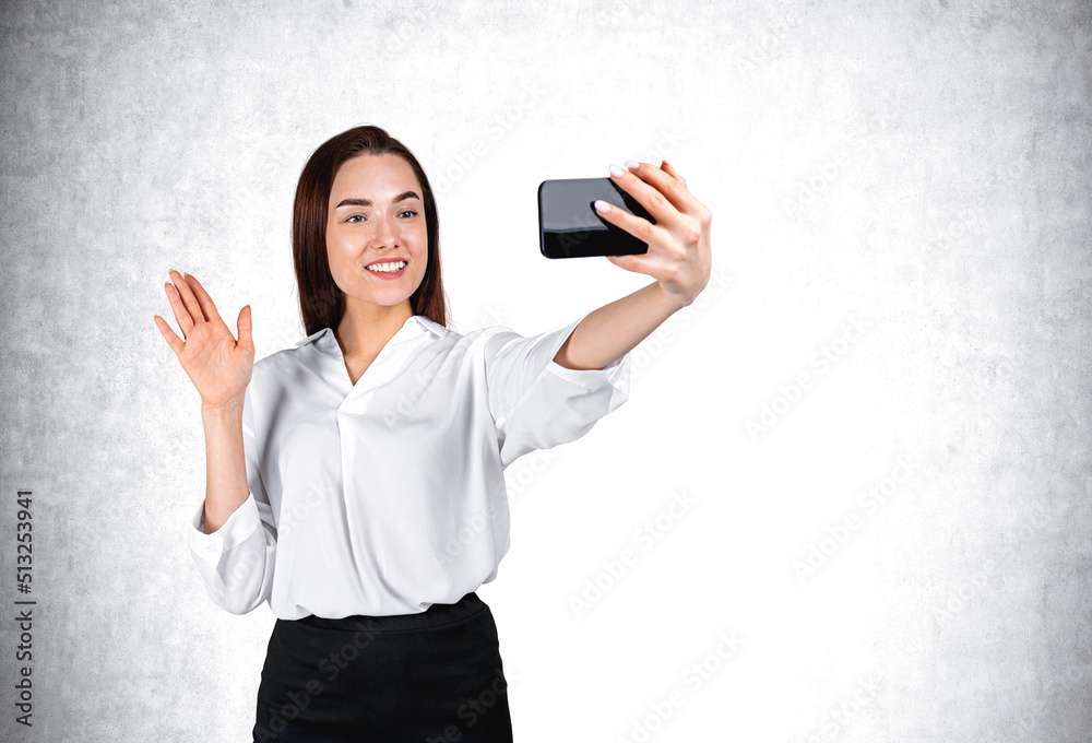 Happy businesswoman with phone in hand, waving on grey background. Copy space Happy businesswoman with phone in hand, waving on grey background. Copy space
