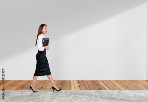 Businesswoman with documents in hands, walking on tiled floor. C