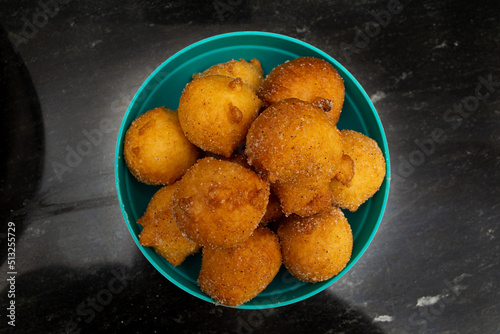 top view of 'bolinho de chuva', traditional brazilian recipe, made of fried dough with sugar and cinnamon, in a blue pot and black background photo