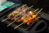 seven skewers on an electric grill, made of pork, chicken, onion, pepper, bovine