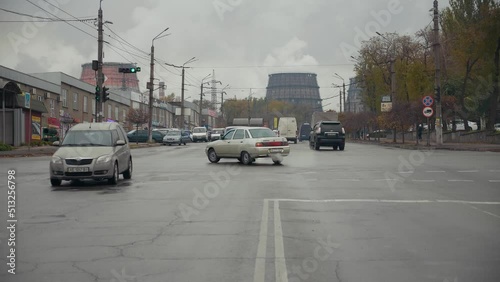Timelapse heavy traffic at the intersection on against the cooling towers of the metal works. Thick steam from the cooling towers rises to the top