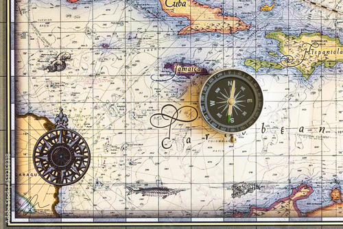 Compass lies on an old map of the Caribbean Sea