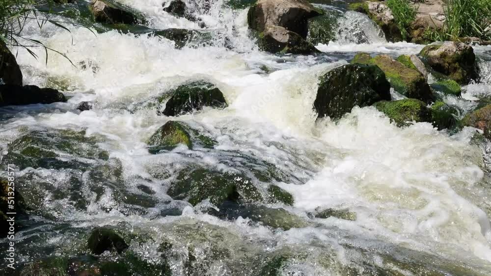 Fast flowing water in the mountain river, water spray from the waves. Texture of seething water, a cascade of a mountain river, bubbles and foam in a stream of water.
